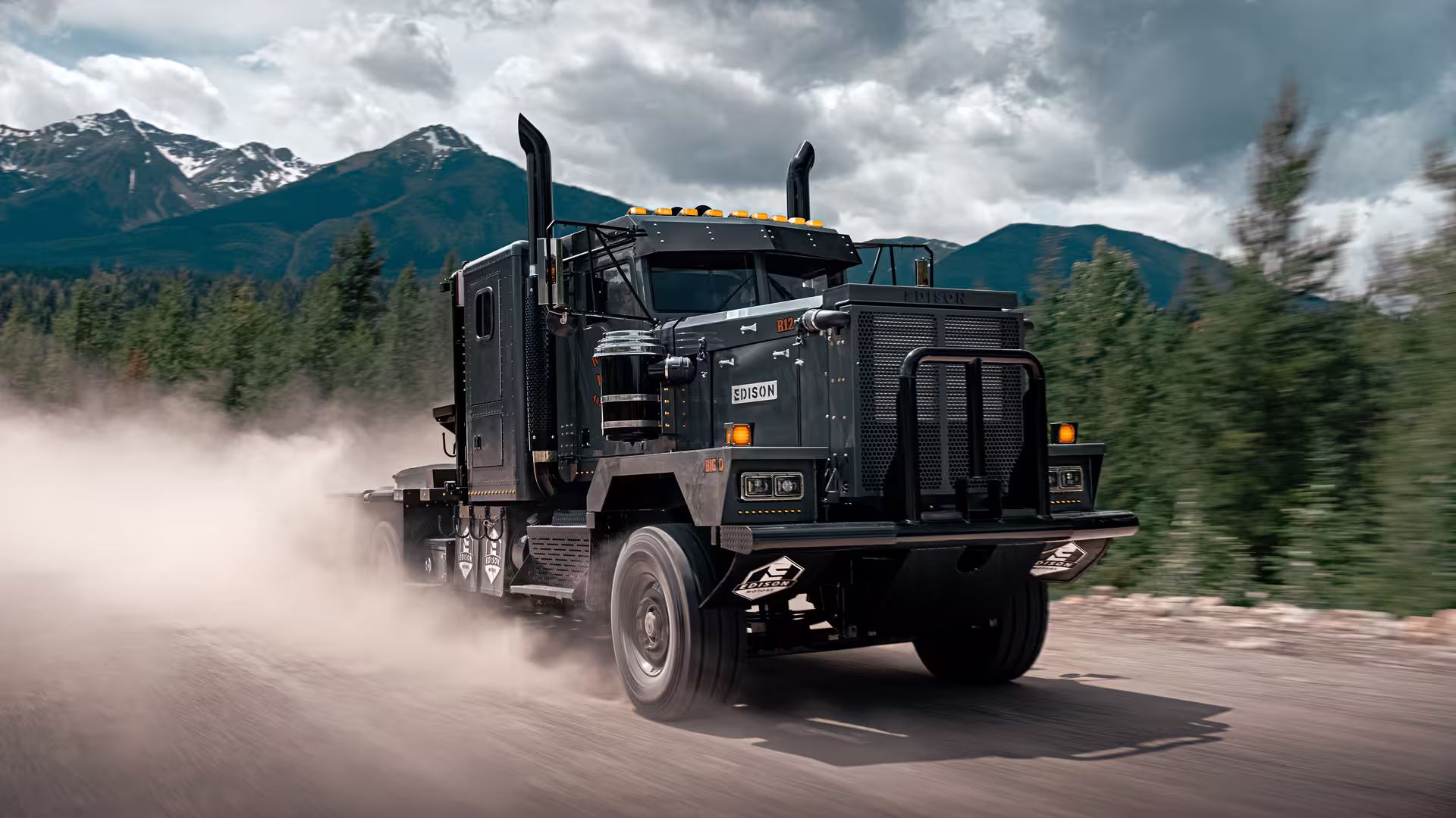 An Edison Motors truck driving on a dusty mountain road in British Columbia