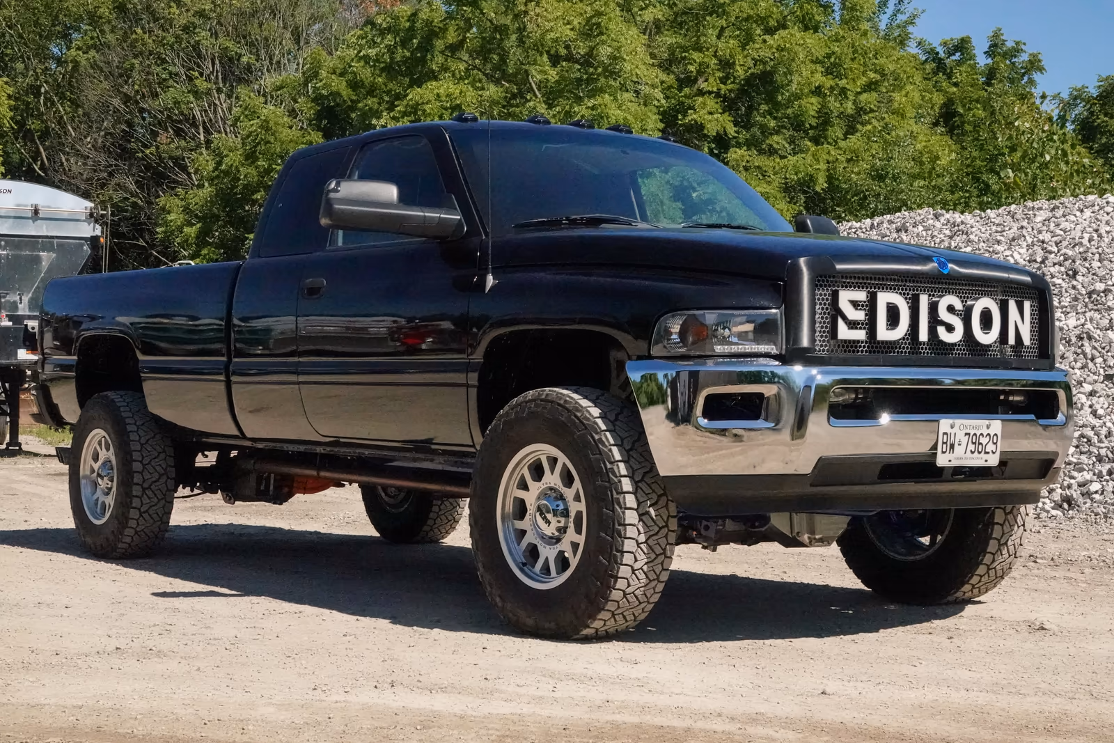 Black Ram pickup with an Edison grille, parked on gravel